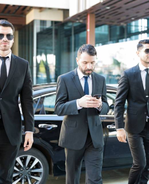 Young Bodyguards Walking By Businessman Service agents escorting entrepreneur messaging on mobile phone at campus